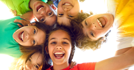 Photo of smiling children arm-in-arms in a circle above the camera