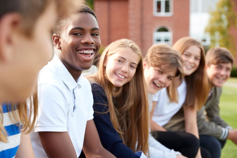 A group of smiling kids in braces sitting on a bench